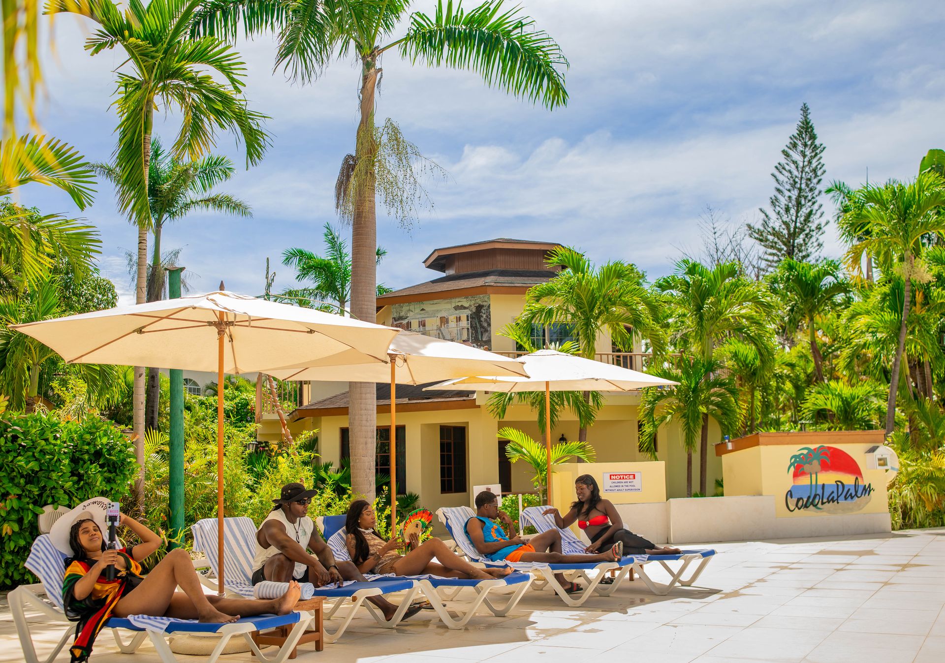 Guests relaxing on loungers beside CocoLaPalm's courtyard pool